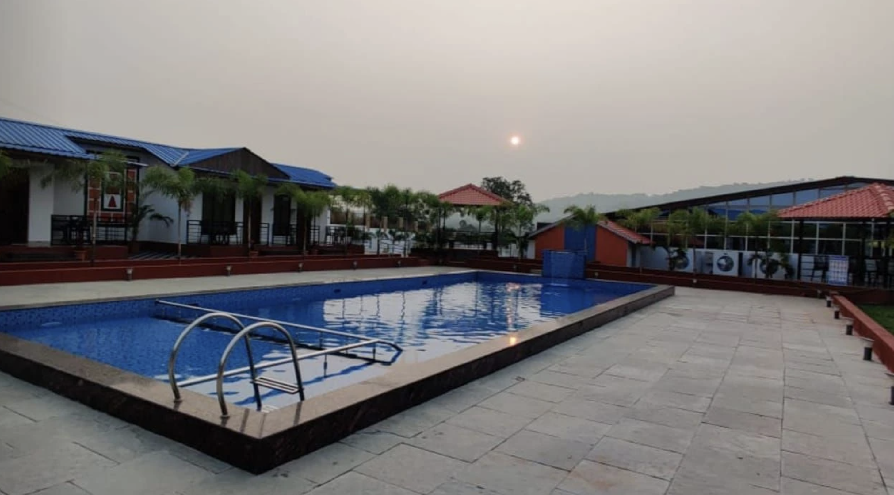 The main pool at dusk, with the room block and palms behind